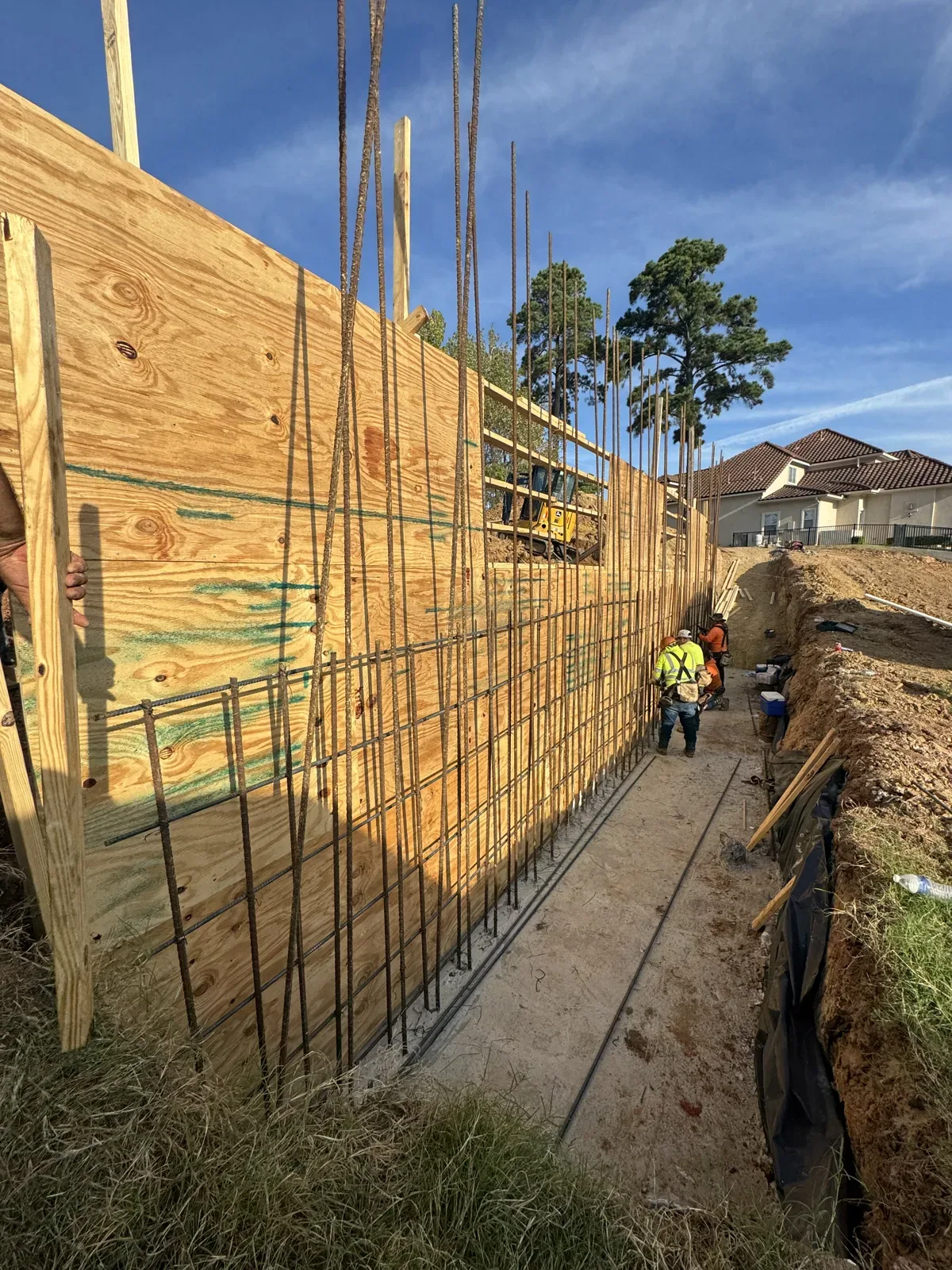 Plywood wall forms and vertical rebar set for a concrete retaining wall pour